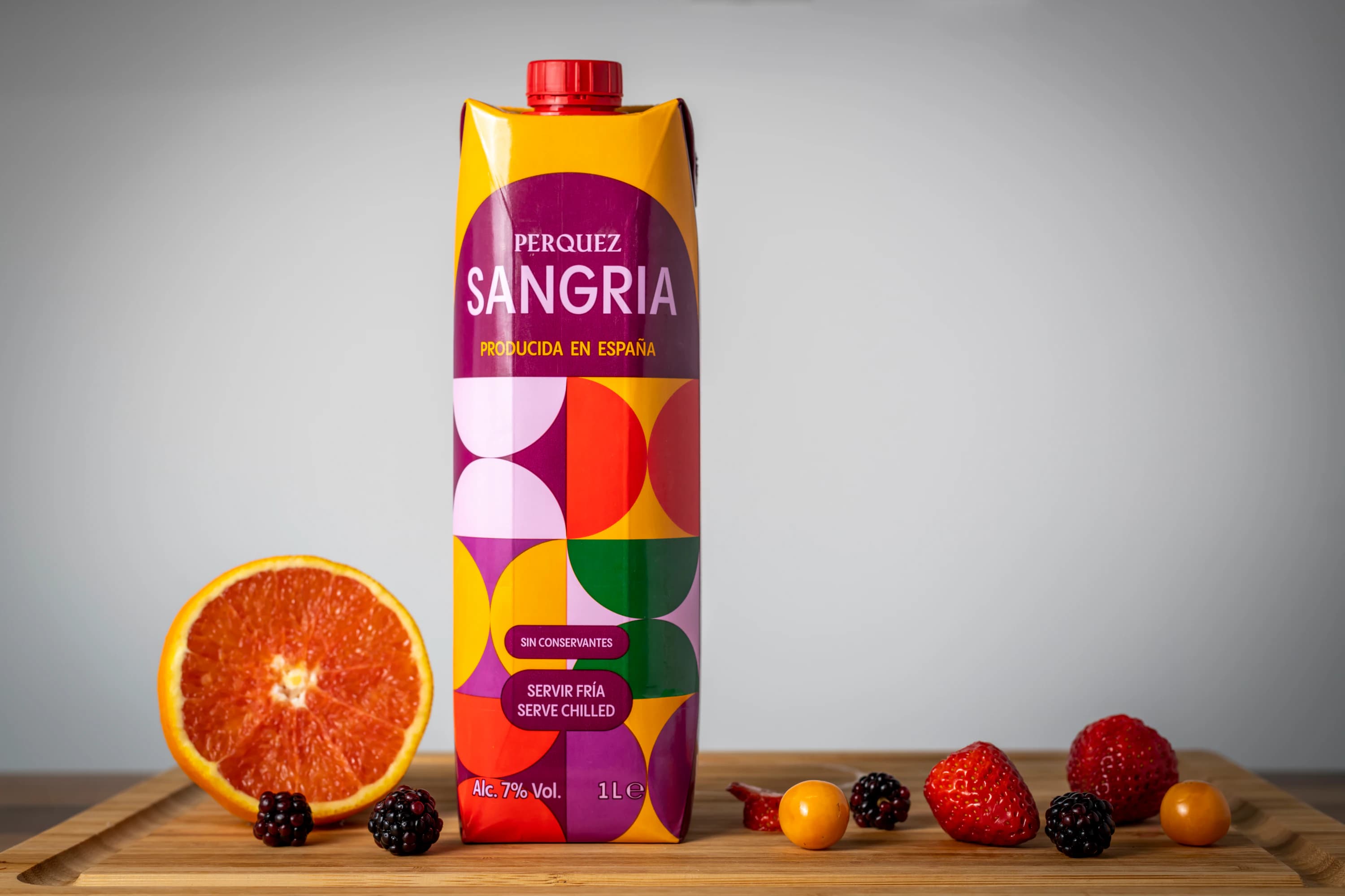 Sangría Perquez con naranjas y frutos rojos sobre una tabla de madera